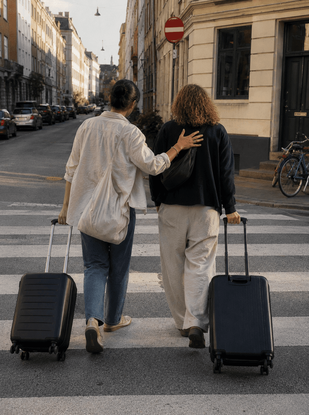 Two travellers with suitcases walking along a Copenhagen street